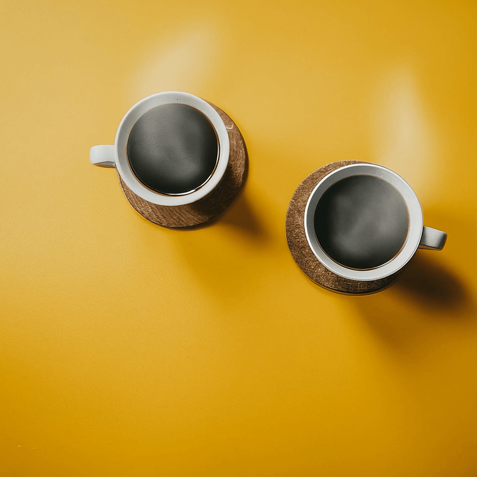 AI Design for Two steaming cups of coffee, cozy home atmosphere, yellow background, for logo with space for text in the middle