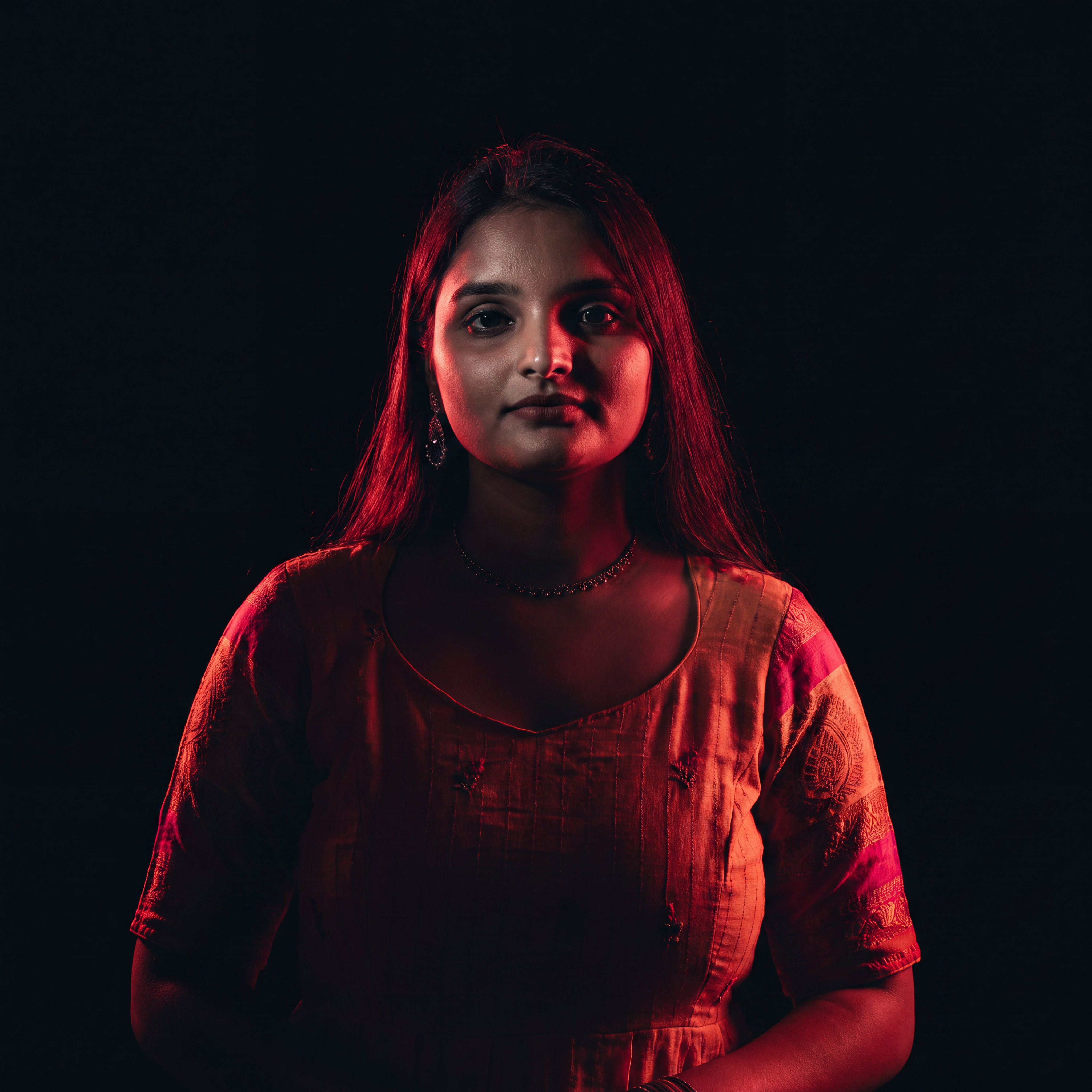 AI Design for Cinematic portrait, straight-on facial expression, hyper-realistic skin texture. Dramatic duotone lighting using only deep matte black (#000000) and rich crimson red (#B00020). Intense crimson directional side lighting sculpting the cheekbones, jawline, and hair texture, transitioning into deep black shadows on the opposite side. Minimalist, solid black background. Premium luxury fashion editorial aesthetic, high-contrast film noir style, sharp facial details, volumetric lighting, 8k resolution, photorealistic, no text, no logos. Use the attached image as the primary composition and structural reference.