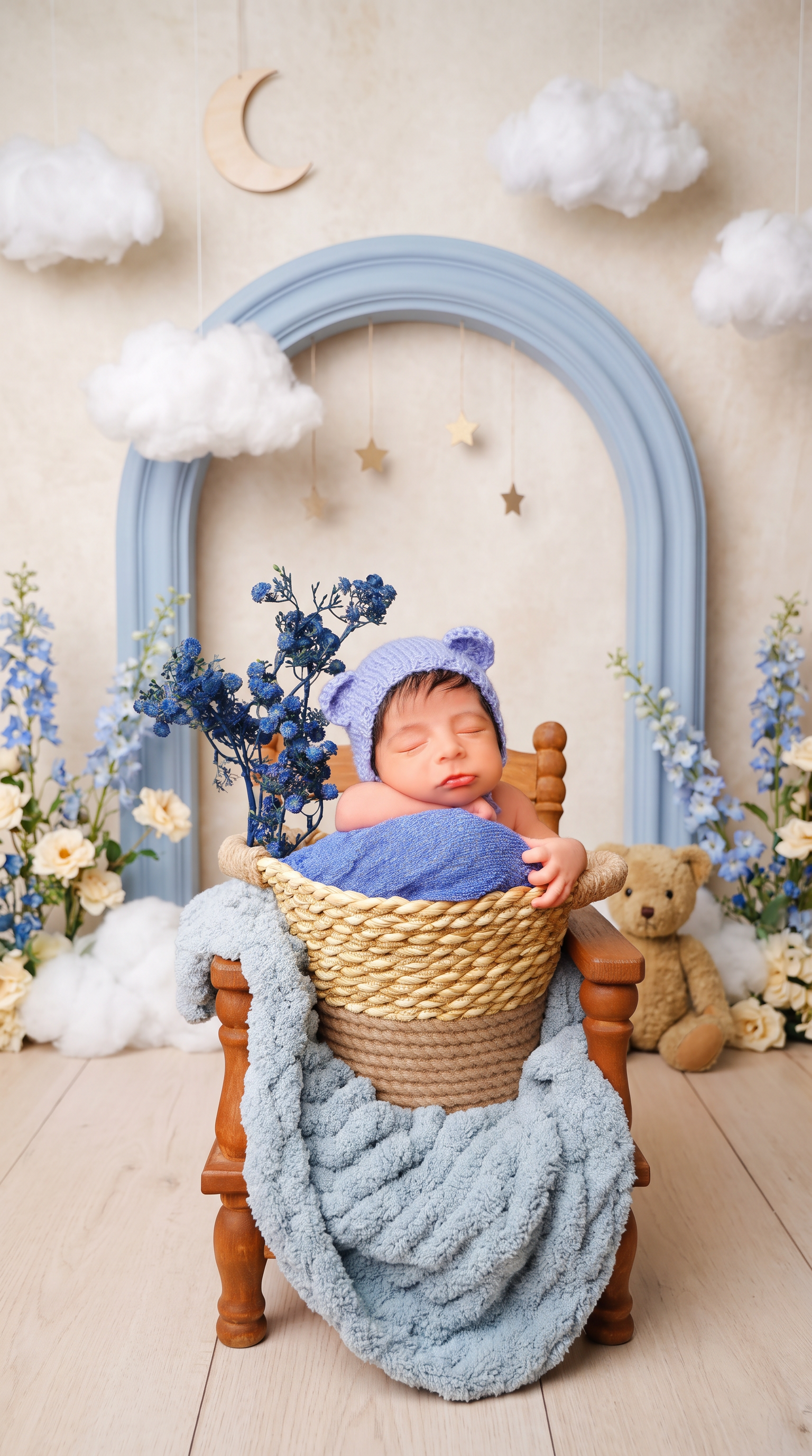 AI Design for Replace only the background and surrounding floor with a professionally styled newborn photography set inspired by a “Little Bear’s Dream Garden.” Create a charming, layered studio scene with a softly textured ivory backdrop, a large powder-blue decorative arch behind the chair, delicate blue delphiniums and cream blossoms arranged along the outer edges, and a few fluffy cloud props suspended at different heights. Add a small pale wooden crescent moon and tiny muted-gold hanging stars in the upper background. Place one small vintage teddy bear on the floor beside the chair, partially behind it and away from the baby. Use a refined palette of dusty blue, warm cream, soft beige, and natural wood.

Make the set playful and imaginative yet polished and believable, like a premium newborn photography session with real handcrafted props—not a digital fantasy illustration. Keep the decorations asymmetrical and thoughtfully spaced, framing the baby without crowding the face or overlapping the existing flowers. Use soft studio lighting consistent with the original light on the baby, gentle background blur, realistic depth, and natural contact shadows beneath the chair and props.

Preserve the baby’s exact identity, facial features, expression, skin tone, natural skin texture, hair, pose, hands, and fingers. Keep the knitted bear-ear bonnet, blue fabrics, existing blue flowers, woven basket, draped blanket, and entire wooden chair completely unchanged. Maintain the original framing, camera angle, and subject proportions. Replace the old background cleanly through all visible gaps between flower stems and chair parts, preserving fine edges and knitted fibers.

Avoid excessive decorations, bright saturated colors, glitter effects, cartoon styling, CGI, artificial skin smoothing, altered anatomy, duplicated objects, floating props, cutout halos, text, and watermarks.