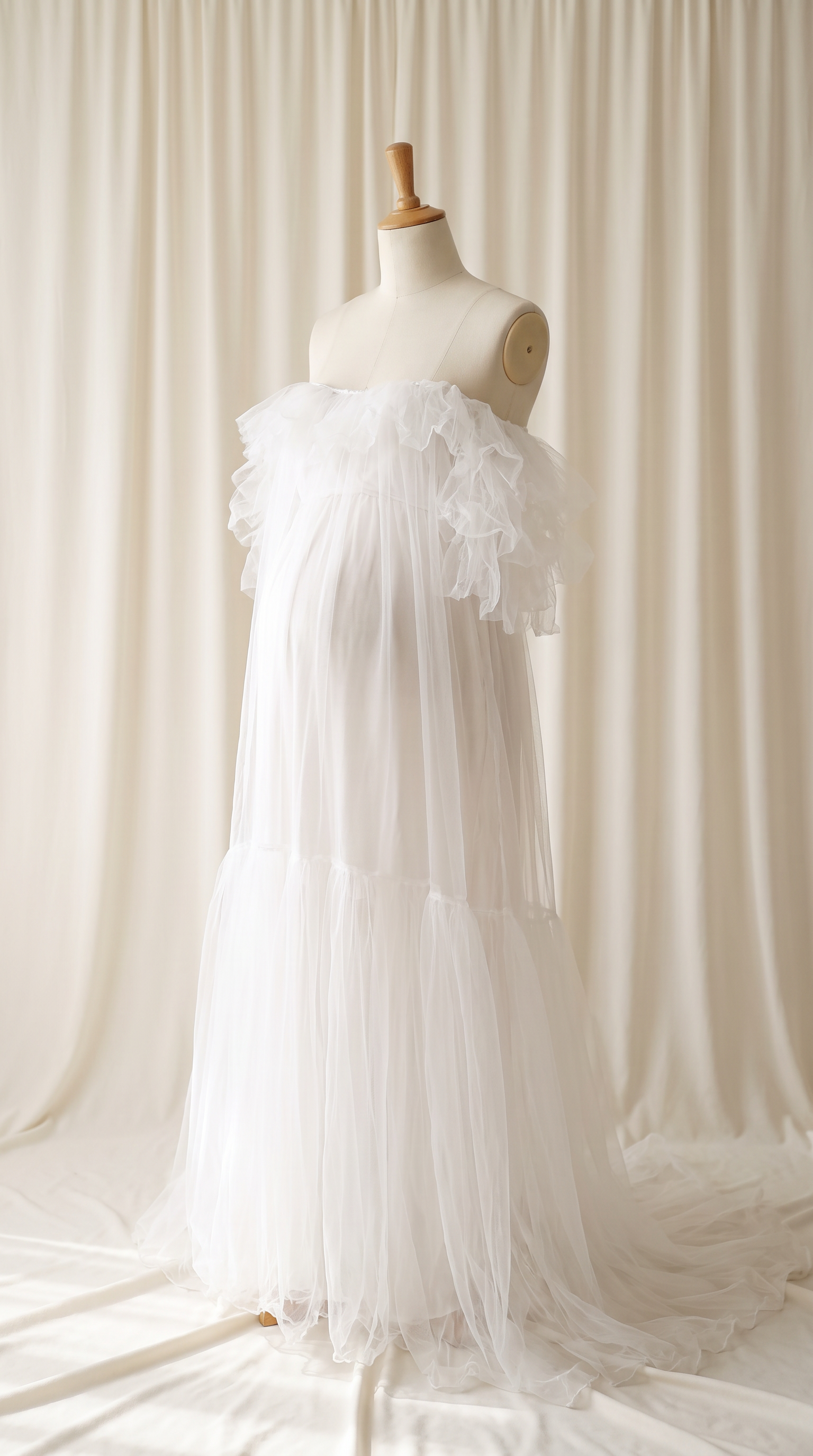 AI Design for 

{
  "task": "Reference-guided maternity garment transfer and studio background replacement",
  "reference_image": "[Attach the original maternity dress photograph]",
  "prompt": "Create a photorealistic maternity fashion product photograph using the attached image as the authoritative garment reference. Transfer the existing dress onto the specified pregnant tailor's dress form; do not create a similar dress, reinterpret the design, beautify it, or redesign it. Change only the original wearer or display form and the surrounding environment. Garment fidelity takes priority over styling and aesthetics. Follow the preservation, mannequin, background, lighting, and framing requirements below.",
  "garment_preservation": {
    "preserve": "Match the visible reference faithfully: hue, saturation, tonal relationships, fabric texture and weight, weave, sheen, transparency, print scale and placement, lace motifs, embroidery, embellishments, seams, neckline, bodice construction, waistline, sleeve cut and length, cuffs, hem, skirt volume, dress length, and any existing train.",
    "fit_and_drape": "Allow only the physically necessary changes in folds and tension caused by fitting the garment to the pregnant form. Preserve the garment's construction and overall silhouette. Fabric must respond naturally to gravity and belly volume, without stretching prints, melting lace, or distorting seams. Support the sleeves naturally without visible arms, hands, rods, or stuffing.",
    "uncertainty": "Do not invent decorative details or unseen garment construction. Keep the reference viewing angle where possible. If the hem or train is cropped out, preserve a comparable crop rather than inventing its appearance. Do not add a train if none is shown."
  },
  "mannequin": {
    "type": "Classic vintage tailor's dress form with a realistic pregnant torso and softly rounded belly, standing upright and centered.",
    "finish": "Matte cream-ivory linen-covered body, gently rounded shoulder ends, and a small round natural-wood neck cap. No head, facial features, arms, hands, human skin, glossy plastic, or exaggerated anatomy.",
    "visibility": "The dress remains the visual focus. Show the form only where the garment naturally exposes it; do not alter the neckline or opacity to hide it. Keep any support discreet and mostly concealed by the garment."
  },
  "background": "A plain warm off-white ivory fabric curtain with soft vertical folds and subtle vintage texture, clean and unpatterned. Matching ivory fabric continues onto the floor in gentle natural folds, creating visual continuity without a hard horizon line. No furniture, props, decorative architecture, or additional objects.",
  "lighting": "Large, soft, diffused daylight from slightly above and to one side; gentle fill, delicate contact shadows, and natural depth. Neutral white balance preserves garment color. Maintain separation between the dress and ivory backdrop without changing either color. No harsh shadows, clipped highlights, strong color casts, or artificial glow.",
  "composition": "Portrait framing, centered subject, straight verticals, realistic proportions, and minimal perspective distortion. Show the complete dress and existing train when supported by the reference, with modest breathing room. Preserve a cropped composition when required to avoid inventing missing garment details.",
  "output": {
    "aspect_ratio": "16:21",
    "orientation": "portrait",
    "style": "High-detail photorealistic product photography; crisp textile detail, natural tonal transitions, no CGI appearance."
  },
  "negative_prompt": "human model, head, face, hair, arms, hands, exposed human skin, non-pregnant torso, oversized belly, glossy plastic mannequin, redesigned dress, altered neckline, missing sleeves, added sleeves, changed hem, invented train, changed color, incorrect print scale, misplaced pattern, missing embellishments, added decorations, warped seams, melted lace, floating fabric, artificial transparency, clutter, furniture, luxury interior, text, logo, watermark, harsh flash, yellow color cast, oversaturation, blur, excessive smoothing, CGI, illustration"
}
