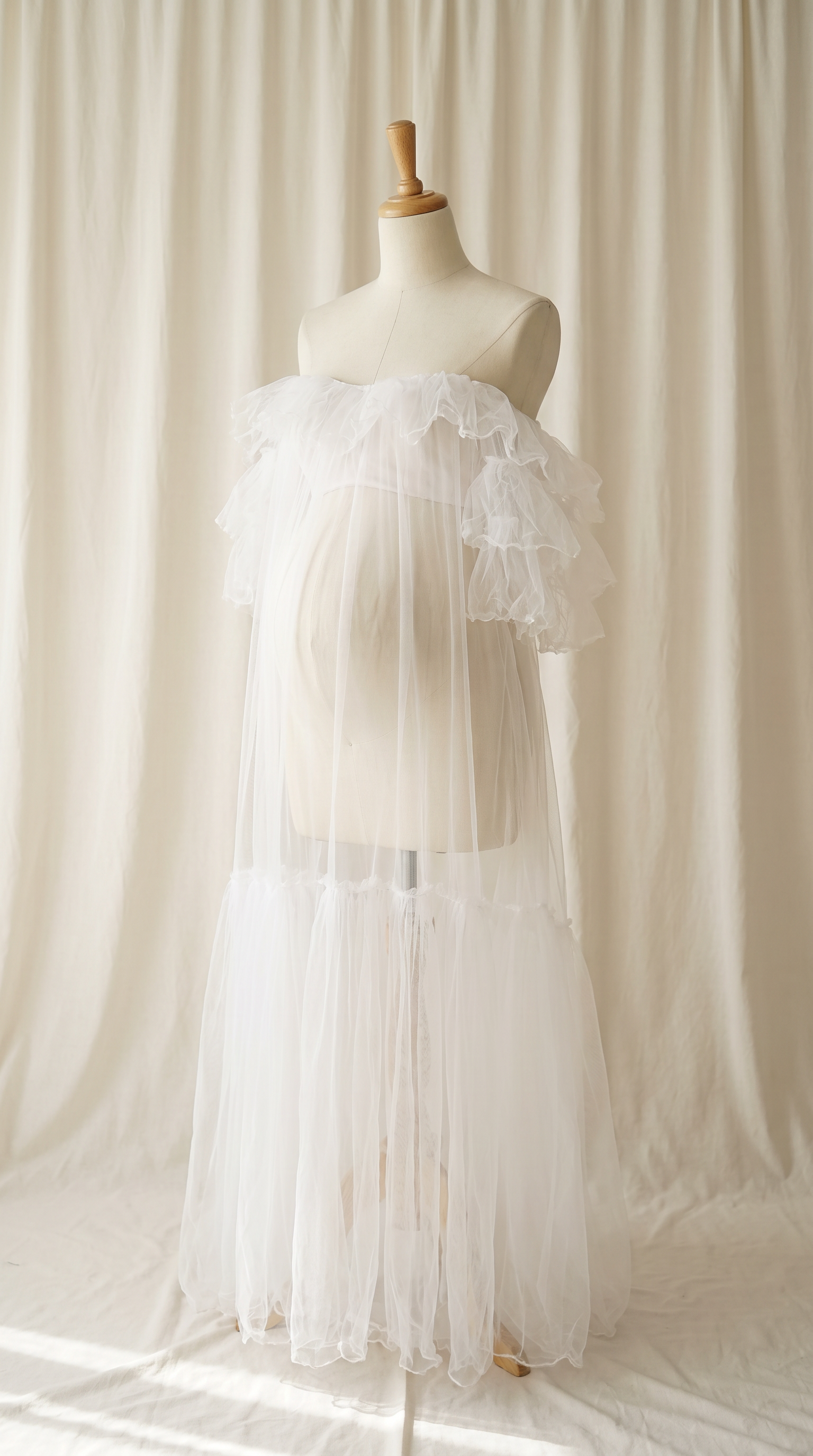 AI Design for 

{
  "task": "Reference-guided maternity garment transfer and studio background replacement",
  "reference_image": "[Attach the original maternity dress photograph]",
  "prompt": "Create a photorealistic maternity fashion product photograph using the attached image as the authoritative garment reference. Transfer the existing dress onto the specified pregnant tailor's dress form; do not create a similar dress, reinterpret the design, beautify it, or redesign it. Change only the original wearer or display form and the surrounding environment. Garment fidelity takes priority over styling and aesthetics. Follow the preservation, mannequin, background, lighting, and framing requirements below.",
  "garment_preservation": {
    "preserve": "Match the visible reference faithfully: hue, saturation, tonal relationships, fabric texture and weight, weave, sheen, transparency, print scale and placement, lace motifs, embroidery, embellishments, seams, neckline, bodice construction, waistline, sleeve cut and length, cuffs, hem, skirt volume, dress length, and any existing train.",
    "fit_and_drape": "Allow only the physically necessary changes in folds and tension caused by fitting the garment to the pregnant form. Preserve the garment's construction and overall silhouette. Fabric must respond naturally to gravity and belly volume, without stretching prints, melting lace, or distorting seams. Support the sleeves naturally without visible arms, hands, rods, or stuffing.",
    "uncertainty": "Do not invent decorative details or unseen garment construction. Keep the reference viewing angle where possible. If the hem or train is cropped out, preserve a comparable crop rather than inventing its appearance. Do not add a train if none is shown."
  },
  "mannequin": {
    "type": "Classic vintage tailor's dress form with a realistic pregnant torso and softly rounded belly, standing upright and centered.",
    "finish": "Matte cream-ivory linen-covered body, gently rounded shoulder ends, and a small round natural-wood neck cap. No head, facial features, arms, hands, human skin, glossy plastic, or exaggerated anatomy.",
    "visibility": "The dress remains the visual focus. Show the form only where the garment naturally exposes it; do not alter the neckline or opacity to hide it. Keep any support discreet and mostly concealed by the garment."
  },
  "background": "A plain warm off-white ivory fabric curtain with soft vertical folds and subtle vintage texture, clean and unpatterned. Matching ivory fabric continues onto the floor in gentle natural folds, creating visual continuity without a hard horizon line. No furniture, props, decorative architecture, or additional objects.",
  "lighting": "Large, soft, diffused daylight from slightly above and to one side; gentle fill, delicate contact shadows, and natural depth. Neutral white balance preserves garment color. Maintain separation between the dress and ivory backdrop without changing either color. No harsh shadows, clipped highlights, strong color casts, or artificial glow.",
  "composition": "Portrait framing, centered subject, straight verticals, realistic proportions, and minimal perspective distortion. Show the complete dress and existing train when supported by the reference, with modest breathing room. Preserve a cropped composition when required to avoid inventing missing garment details.",
  "output": {
    "aspect_ratio": "16:21",
    "orientation": "portrait",
    "style": "High-detail photorealistic product photography; crisp textile detail, natural tonal transitions, no CGI appearance."
  },
  "negative_prompt": "human model, head, face, hair, arms, hands, exposed human skin, non-pregnant torso, oversized belly, glossy plastic mannequin, redesigned dress, altered neckline, missing sleeves, added sleeves, changed hem, invented train, changed color, incorrect print scale, misplaced pattern, missing embellishments, added decorations, warped seams, melted lace, floating fabric, artificial transparency, clutter, furniture, luxury interior, text, logo, watermark, harsh flash, yellow color cast, oversaturation, blur, excessive smoothing, CGI, illustration"
}
