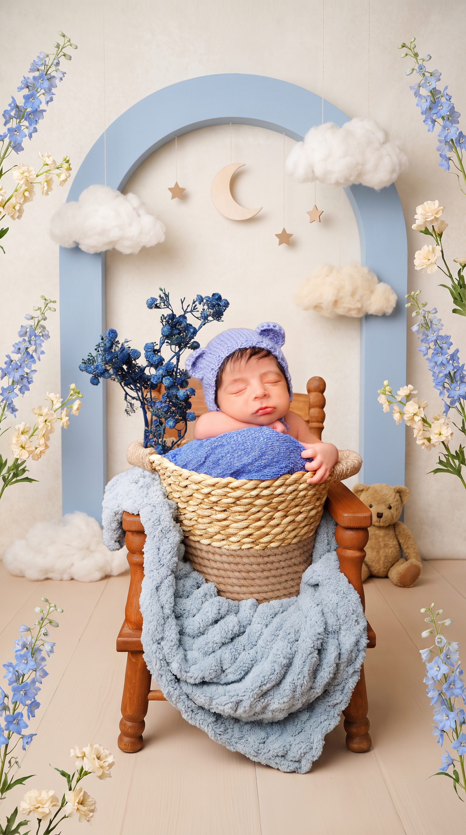 AI Design for Replace only the background and surrounding floor with a professionally styled newborn photography set inspired by a “Little Bear’s Dream Garden.” Create a charming, layered studio scene with a softly textured ivory backdrop, a large powder-blue decorative arch behind the chair, delicate blue delphiniums and cream blossoms arranged along the outer edges, and a few fluffy cloud props suspended at different heights. Add a small pale wooden crescent moon and tiny muted-gold hanging stars in the upper background. Place one small vintage teddy bear on the floor beside the chair, partially behind it and away from the baby. Use a refined palette of dusty blue, warm cream, soft beige, and natural wood.

Make the set playful and imaginative yet polished and believable, like a premium newborn photography session with real handcrafted props—not a digital fantasy illustration. Keep the decorations asymmetrical and thoughtfully spaced, framing the baby without crowding the face or overlapping the existing flowers. Use soft studio lighting consistent with the original light on the baby, gentle background blur, realistic depth, and natural contact shadows beneath the chair and props.

Preserve the baby’s exact identity, facial features, expression, skin tone, natural skin texture, hair, pose, hands, and fingers. Keep the knitted bear-ear bonnet, blue fabrics, existing blue flowers, woven basket, draped blanket, and entire wooden chair completely unchanged. Maintain the original framing, camera angle, and subject proportions. Replace the old background cleanly through all visible gaps between flower stems and chair parts, preserving fine edges and knitted fibers.

Avoid excessive decorations, bright saturated colors, glitter effects, cartoon styling, CGI, artificial skin smoothing, altered anatomy, duplicated objects, floating props, cutout halos, text, and watermarks.