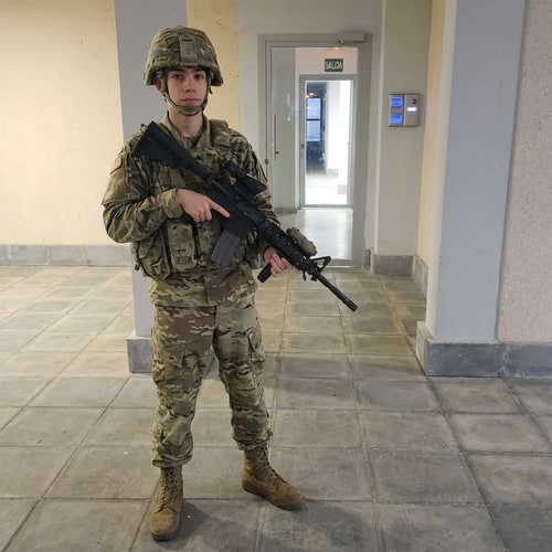 AI Design for haz que el chico de la foto tenga vestimenta militar y este agarrando una M4