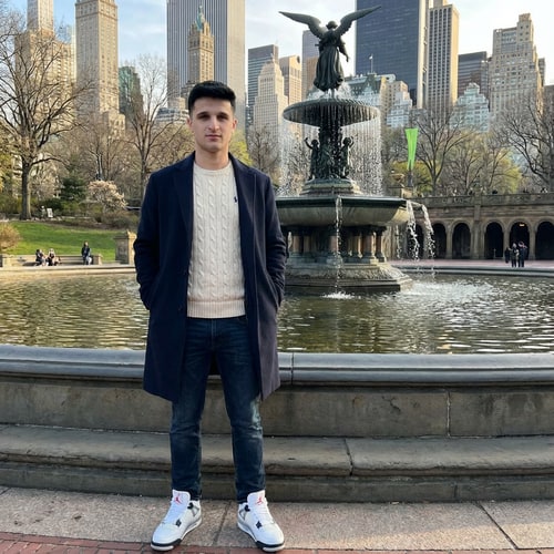 AI Design for Szerkeszd meg ezt a képet úgy hogy állok 1 helyen Newyorkba valami szép szökőkutnál. Armani kabátba alul kötött ralp lauren pulóverbe, Jordan 4 cipőbe. Illetve az arcot ne torzitsd el ez az én arcom, minden legyen realisztikus