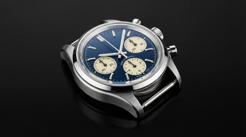 AI Design for A pristine, high-resolution close-up of a single vintage mechanical watch (chronograph) — Tight macro shot, focusing sharply on the polished bezel and intricate dial details; shallow depth of field; viewed slightly from above (high angle) — Highly chromatic palette of brushed stainless steel, deep sapphire blue, and creamy ivory accents — Dramatic, professional studio lighting; strong directional key light creating sharp specular highlights on the metal and glass; high contrast, sophisticated mood — Hyper-detailed photorealism; advertising photography quality, suitable for a luxury product campaign; ensure absolutely no visual artifacts or blur; ensure perfect color balance — Generate a technically perfect, flawless image; avoid watermarks, visible brushstrokes, or digital noise — Minimalist matte black surface; subtle, soft reflection beneath the object.