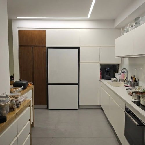 AI Design for Change the refrigerator color to white.
• Reduce the refrigerator depth so it is fully flush with the cabinetry. Currently, the refrigerator protrudes 10 cm beyond the cabinet line; it should not protrude at all.
• On the opposite side, change the finish of the tall cabinets to a brown tone.
• Lower the height of the tall cabinets so they match the height of the tall cabinets in the refrigerator area, creating one consistent height for all tall cabinets in the kitchen.
• Continue the wall line above the cabinets so it wraps around them, creating a framed and cohesive look.