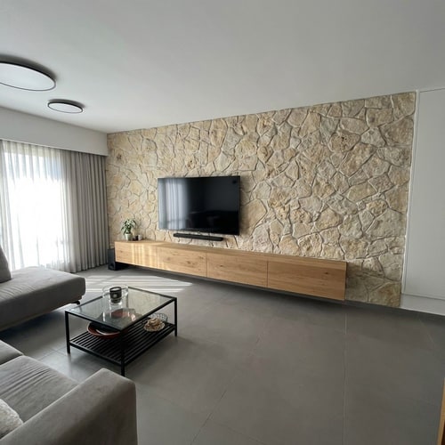 AI Design for Photorealistic interior redesign of a modern living room wall.
Wall dimensions: 267 cm height, 650 cm width.
Remove the gray armchair and the yellow armchair completely.
Replace the existing TV cabinet with a 400 cm long floating cabinet made of natural matte wood, minimalist modern design, 50 cm height, installed 20 cm above the floor, clean handleless look.
Apply natural stone wall cladding identical to the provided reference stone image. The stone pattern reference size is 114 cm wide by 80 cm high. Install the stone cladding starting from the window area and extend horizontally to 500 cm width across the wall.
Highly realistic materials, natural lighting, accurate proportions, sharp details, architectural visualization, ultra-realistic texture, professional interior photography style, 8K resolution.