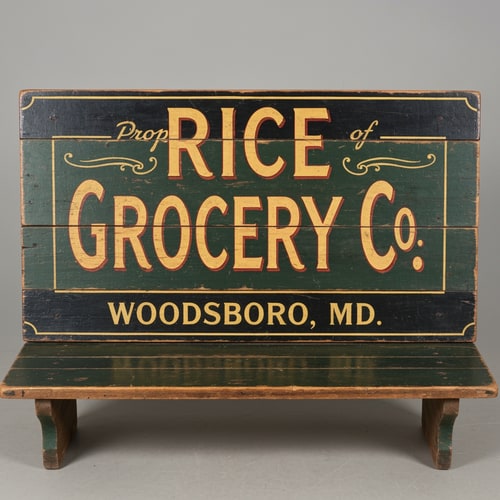 AI Design for A vintage wooden bench designed like an old general store advertising sign, viewed straight from the front (perfect frontal view, no perspective distortion). The top surface is flat and clearly visible like a signboard. It has hand-painted, slightly worn lettering in a classic 19th-century style. The main text reads “Rice Grocery Co.” in large, bold, warm yellow and red lettering. Above it in smaller text: “Property of”. Below it: “Woodsboro, MD.” The wood is aged, slightly weathered with visible grain and subtle paint wear. Colors are dark green, black, and rustic tones. The bench has simple wooden legs visible underneath. Lighting is soft and natural, background neutral and unobtrusive.