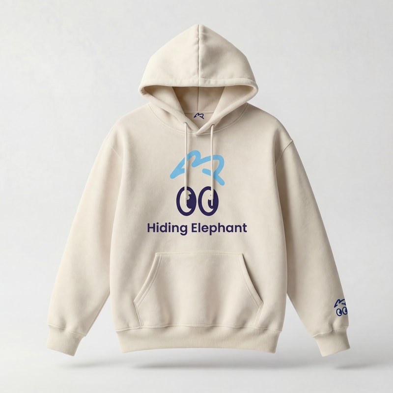 Ultra realistic studio product photo of a beige oversized hoodie, front-facing, no model.
Premium cotton fabric, soft texture, natural folds, high-quality stitching,
fashion e-commerce style, clean and minimal.
Apply full “Hiding Elephant” branding to the hoodie:
— Main chest branding:
centered playful eye icon inspired by the Hiding Elephant logo,
rounded friendly cartoon eyes with a small eyebrow above,
printed in soft sky blue and deep navy.
— Brand name:
“Hiding Elephant” placed under the icon in clean modern sans-serif typography,
balanced spacing, subtle and confident.
— Secondary branding details:
small eye icon embroidered near the left sleeve cuff,
tiny eyebrow graphic on the back near the neck collar,
minimal and tasteful.
Branding style:
friendly, smart, playful but premium,
not childish, not loud, modern startup streetwear.
Printing style:
high-quality screen print and embroidery mix,
ink integrated naturally into fabric.
Lighting:
soft diffused studio light,
gentle shadows, realistic depth.
Background:
light neutral studio background (off-white / light gray),
no texture, no gradients.
Ultra realistic product mockup,
fashion brand presentation,
sharp focus, high detail, professional photography.