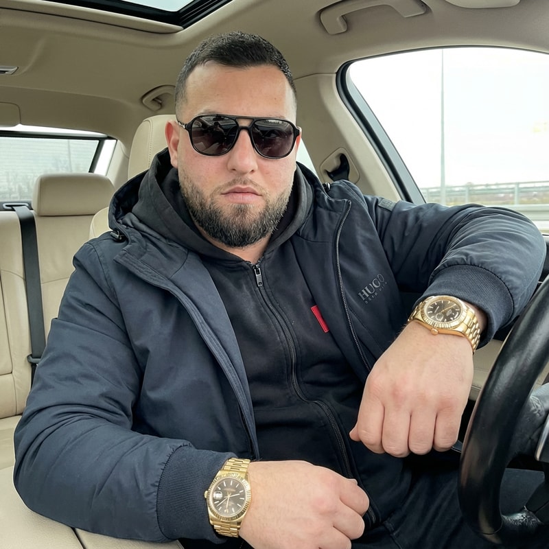 Szerkeszd meg ezt a képet úgy hogy van rajta 1 Hugoboss pulóver kabáttal. Benne ül a BMW-be. Kezén 1 arany rolex óra. És van rajta 1 napszemüveg. Az arca és a kép 100%-ban realisztikus legyen