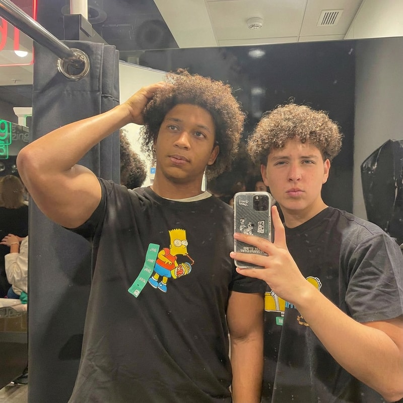 quiero que el chico de la izquierda tenga mas grande los brazos y con la misma pose, sin cambiar caras