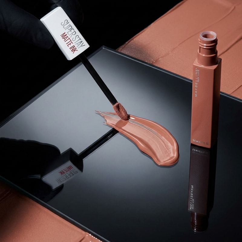“Glass Reflection + Liquid Stroke
Prompt:
Lipstick with applicator creating a smooth swipe stroke on glossy glass surface, reflection visible, nude tone liquid texture, black + nude contrast background, cinematic lighting.”