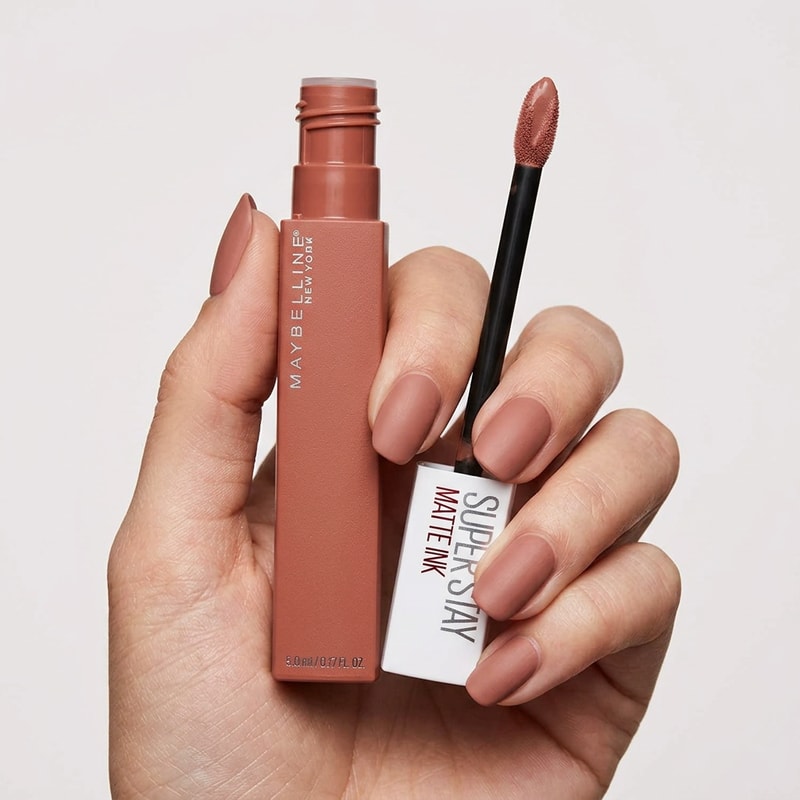 close up cinematic product photo of the uploaded lip product held naturally in a female hand with the applicator removed and the visible next to the bottle the nails are really manicured and painted in the same colour has the lip product shade clean plain Studio background soft Beauty Studio lighting minimal composition sharp product  focus realistic skin texture premium cosmetic advertisement size give the uploaded product exactly as as it is do not change the product shspde design packaging cap logo label colour